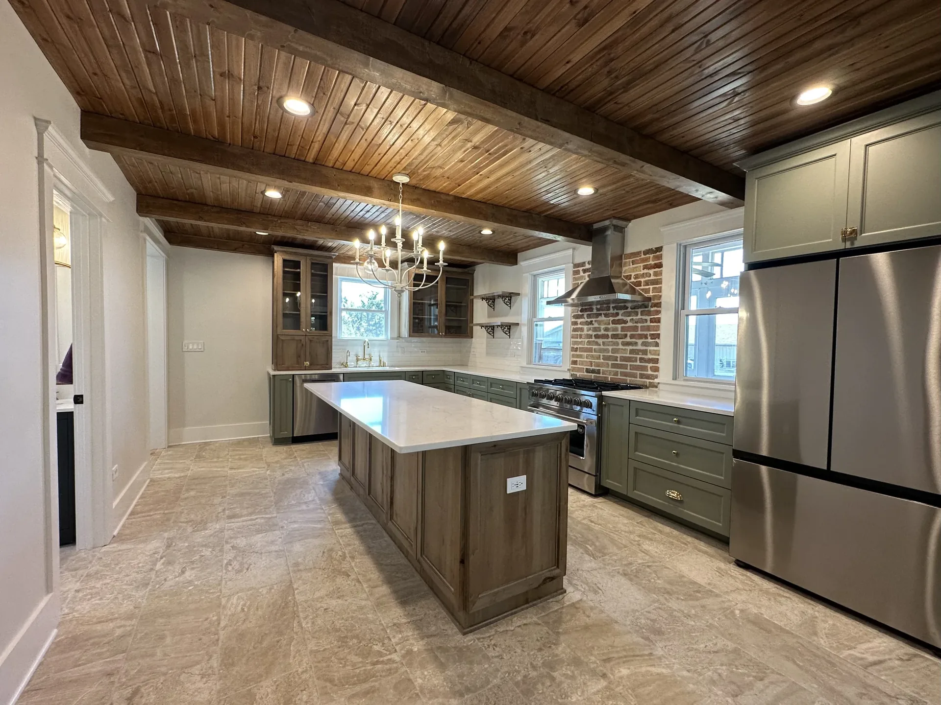 Finished kitchen with beamed ceiling, island, and stainless appliances