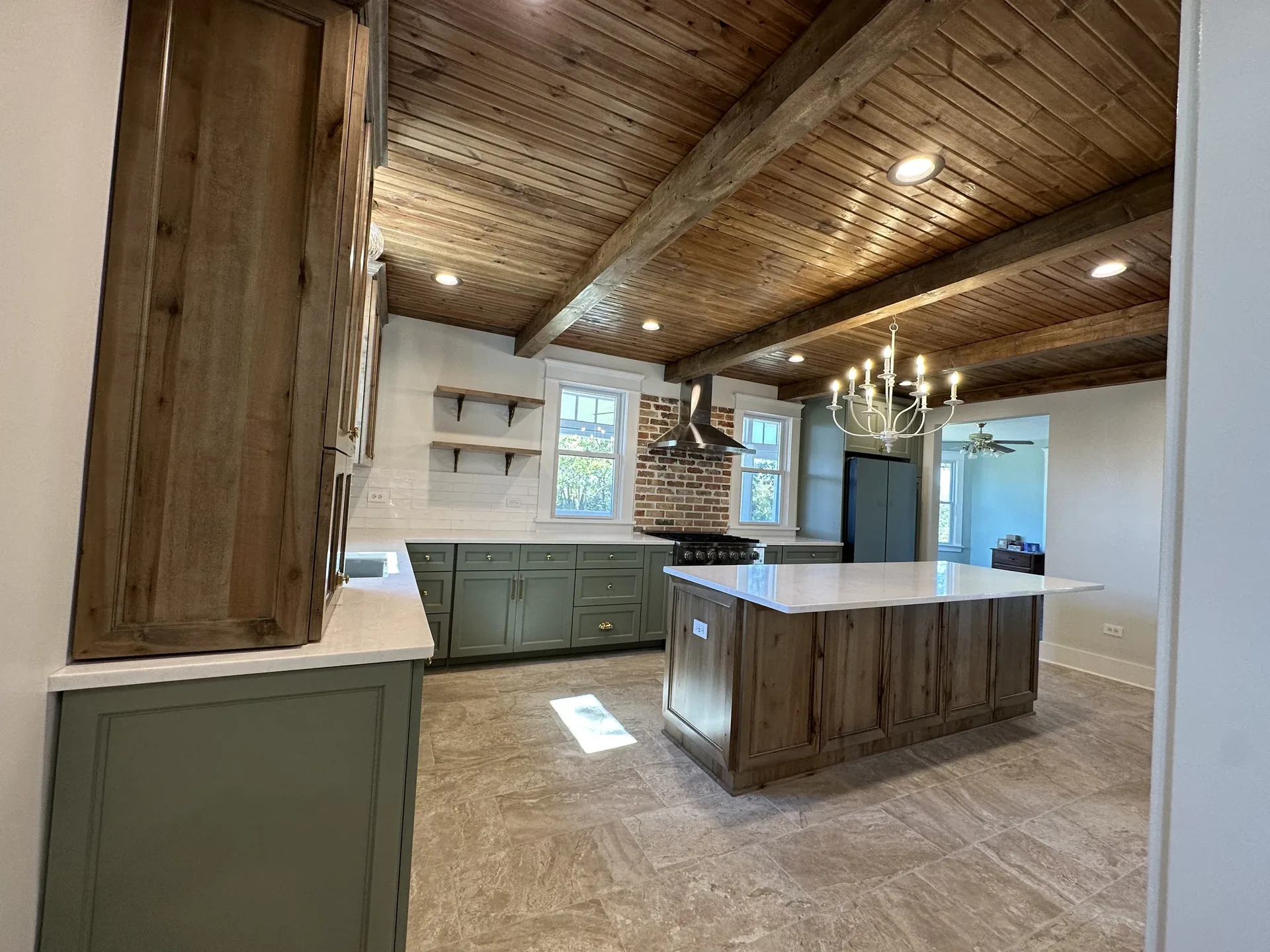 Open-concept kitchen with island, custom cabinetry, and exposed beams