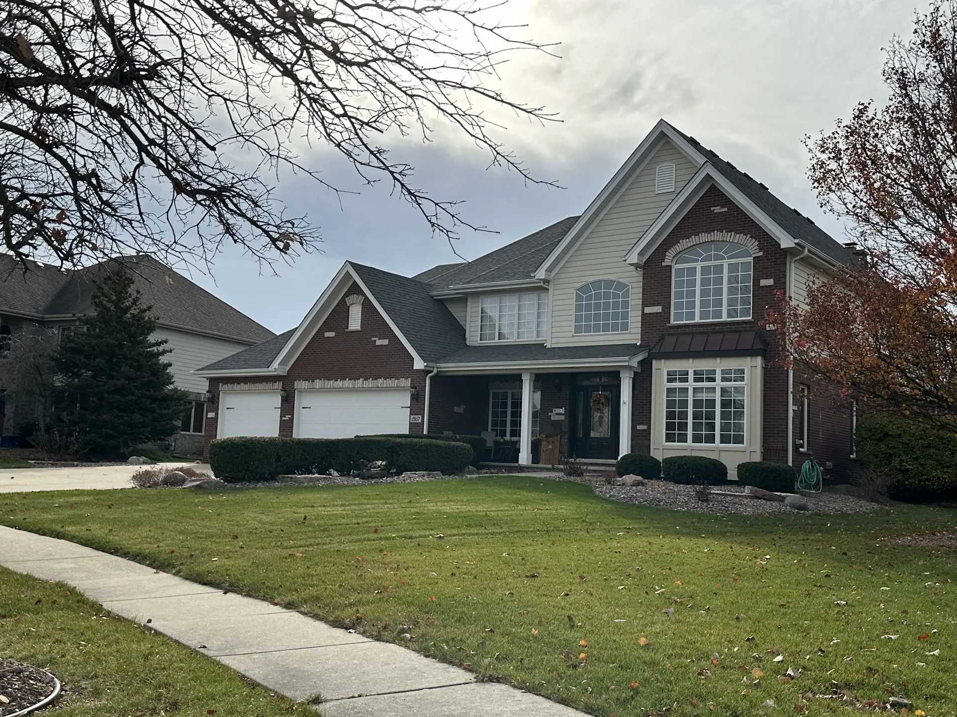 Finished custom home exterior with brick, siding, and mature landscaping
